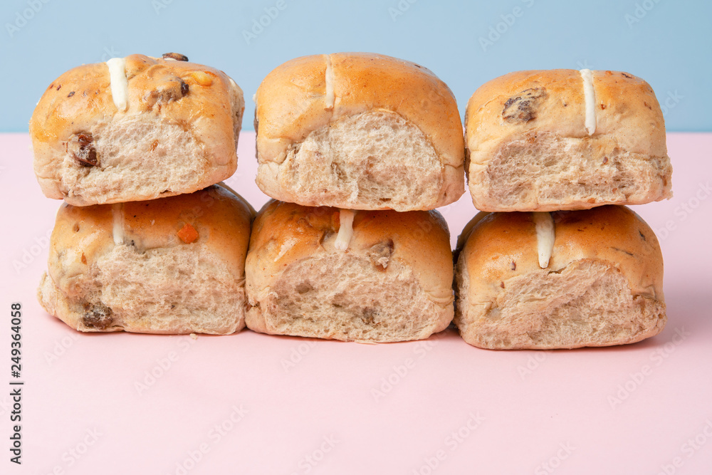Six hot cross buns, traditional British Easter food on pink and blue background, selective focus