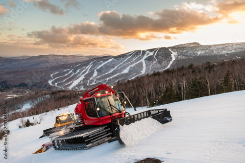 A fleet of snowcats grooming Spruce Peak at dusk with Mt. Mansfield in the background, Stowe, Vermont, USA