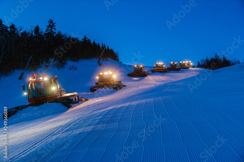 Fleet of snowcats grooming Spruce Peak at dusk, Stowe, Vermont, USA