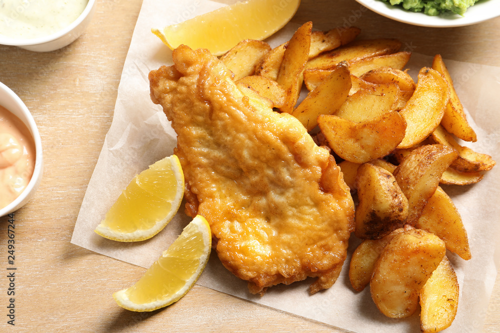 British traditional fish and potato chips on wooden background, closeup British traditional fish and potato chips on wooden background, closeup