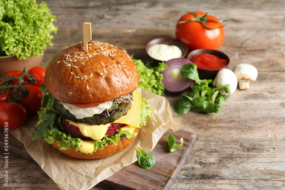 Board with vegan burger and vegetables on wooden table. Space for text Board with vegan burger and vegetables on wooden table. Space for text