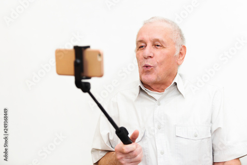 Old active man taking selfie with mobile phone isolated on grey background photo