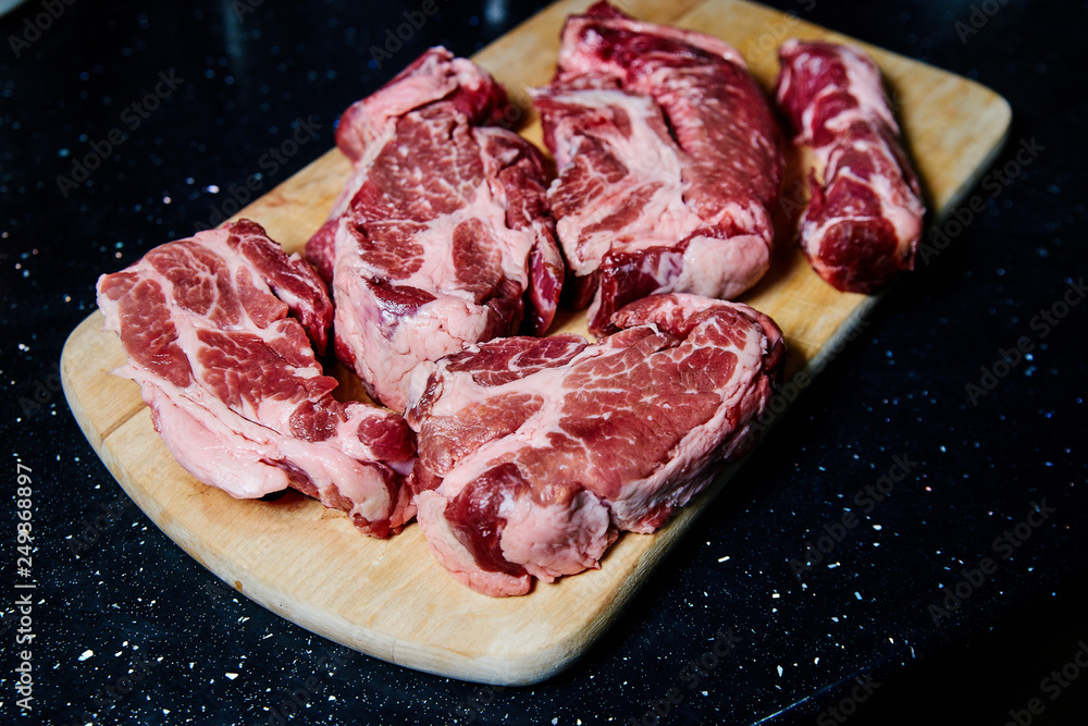 Fresh raw meat pork neck on wooden Board on black table