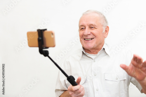 Old active man taking selfie with mobile phone isolated on grey background