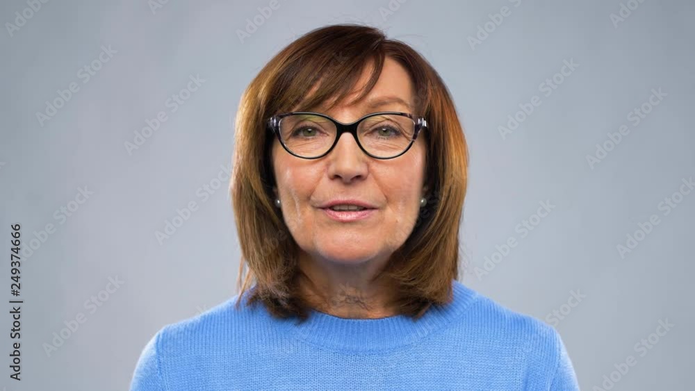 communication, age and people concept - happy senior woman in glasses having video chat or interview over grey background communication, age and people concept - happy senior woman in glasses having video chat or interview over grey background