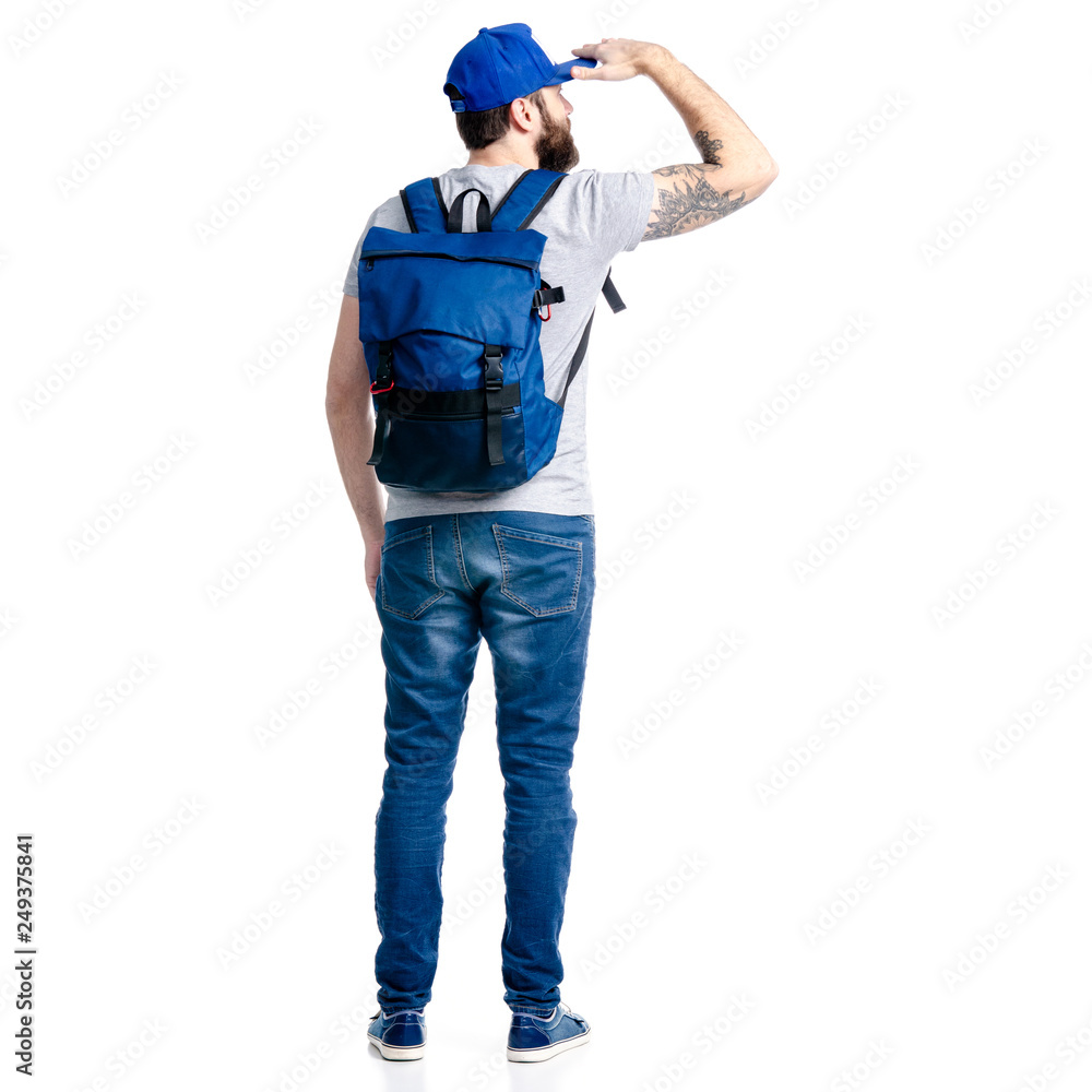 A man tourist in jeans and cap, blue backpack standing looking into the distance on white background isolation, back view A man tourist in jeans and cap, blue backpack standing looking into the distance on white background isolation, back view