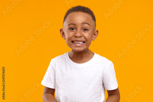 Human emotions, feelings and reaction. Positive emotional dark skinned little boy of 10 year old making funny facial expression, smiling broadly, showing white perfect teeth, posing isolated © Anatoliy Karlyuk