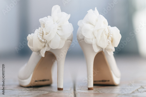 View of white bridal shoes and artificial flowers