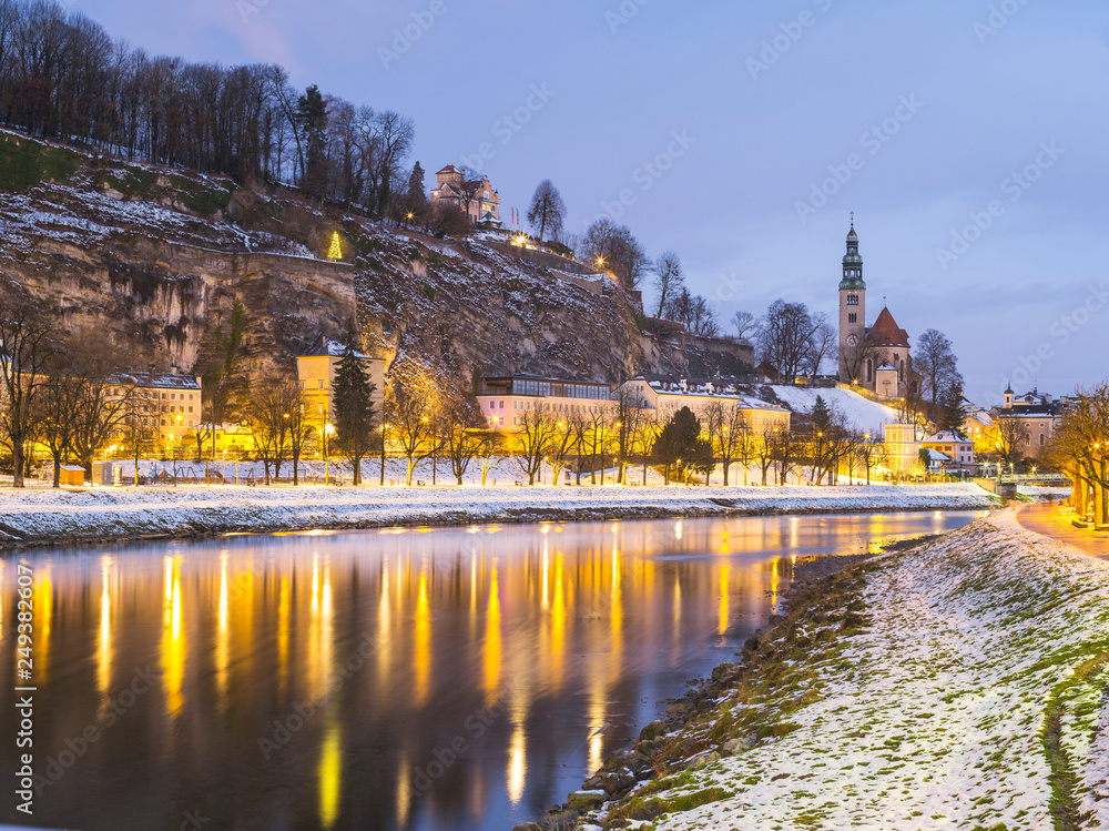 view to river and church with golden reflections in water in Salzburg in Austria