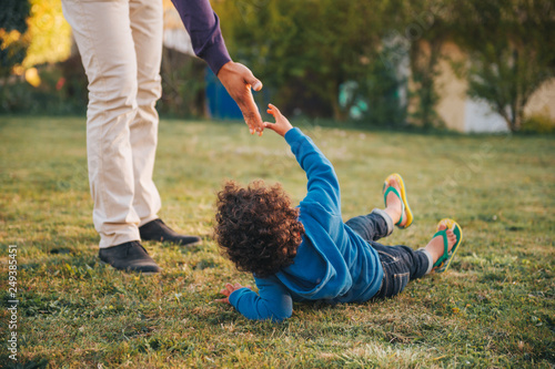 Fotografie Father giving a helping hand to his son lying on the ground