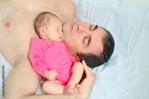 A newborn girl falls asleep on her father