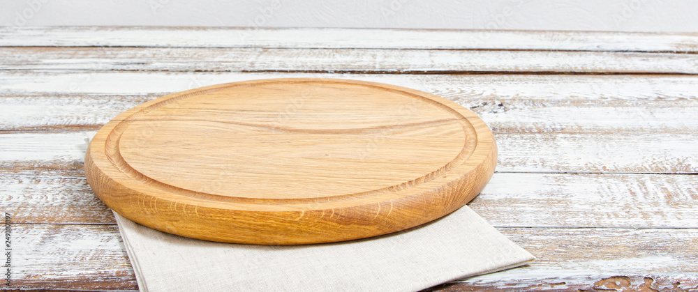 empty pizza board on empty wooden table with tablecloth,napkin - top view