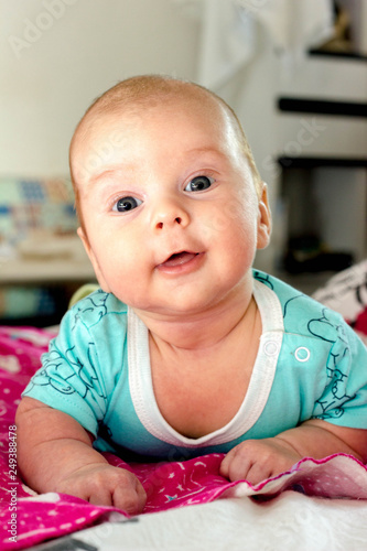 The charming child in blue smiles and lies on a stomach