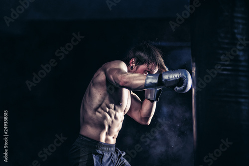 Wallpaper Mural Strong and muscular guy practicing punching the boxing bag. Moody environment. Edgy edit style. Torontodigital.ca