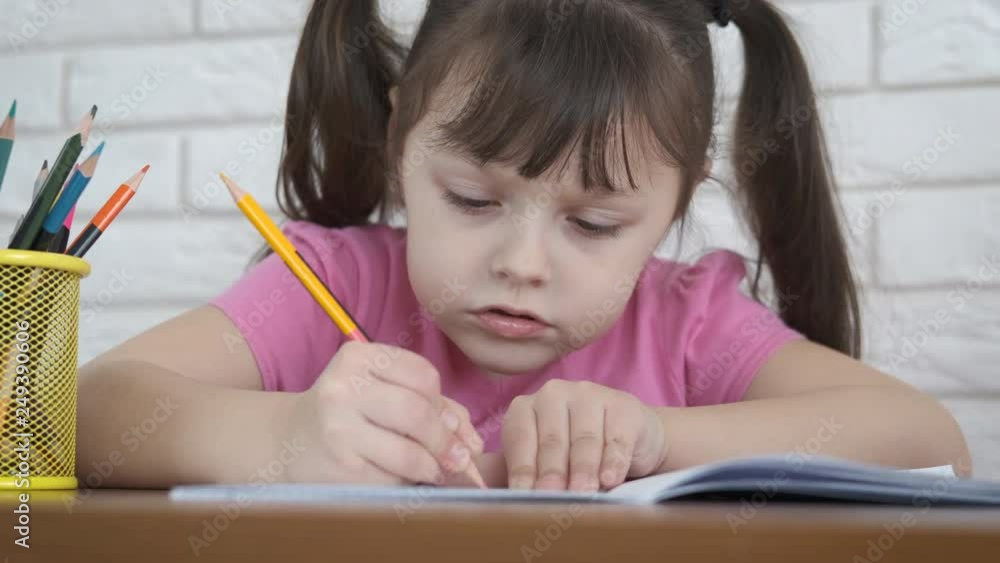A child learns to write. A cute little girl learns to write letters in a notebook with diligence. A child learns to write. A cute little girl learns to write letters in a notebook with diligence.