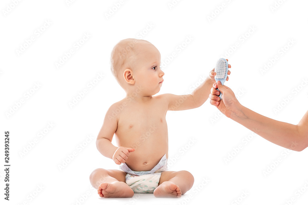Adorable baby boy is trying to brush his hair isolated. Mom taking care of infant child . hygiene Adorable baby boy is trying to brush his hair isolated. Mom taking care of infant child . hygiene