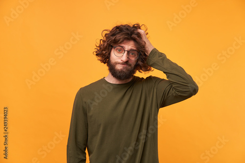 Fotografi Portrait of bearded casually dressed man in glasses with dark curly hair looking
