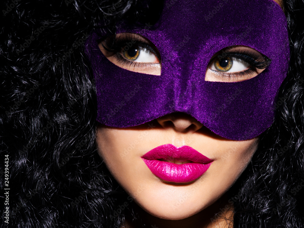 Beautiful  woman with black hairs and violet theatre mask on face.