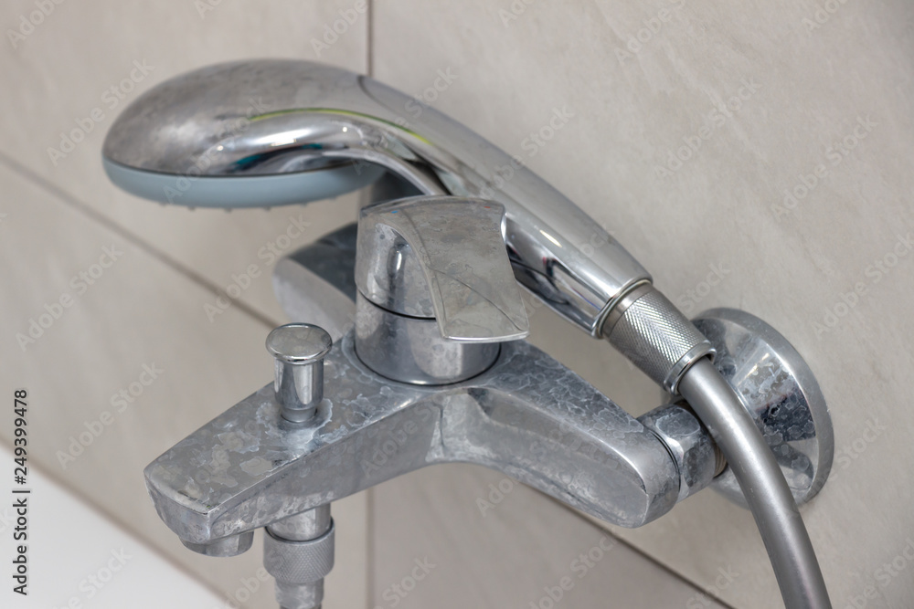 Close-up of shower mixer faucet with limescale, white chalky deposit and stains. Formed on the plumbing system by a combination of soap residues and hard water. Concept of cleaning limescale plumbing Close-up of shower mixer faucet with limescale, white chalky deposit and stains. Formed on the plumbing system by a combination of soap residues and hard water. Concept of cleaning limescale plumbing