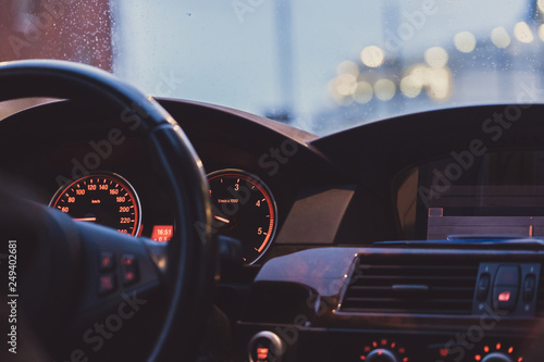 Interior view of a car with focus on the gauges and clock and bokhed bolls in the windshield photo