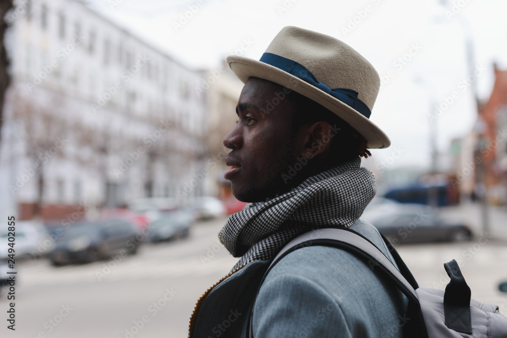 African american man in coat and hat walking along city street African american man in coat and hat walking along city street
