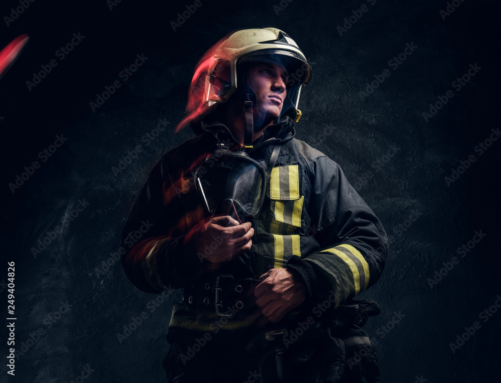 Manly firefighter in helmet looks sideways in studio on black background Manly firefighter in helmet looks sideways in studio on black background