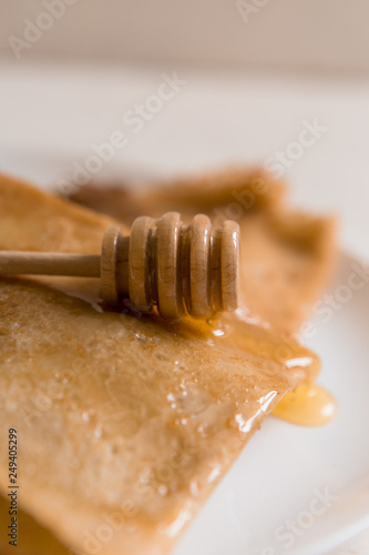 traditional Russian pancakes with honey on a light background.carnival.copy spase.pancake week.pancakes with honey syrup on a white plate 