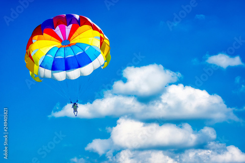 Paragliding parachuting sport in the blue cloudy sky.
