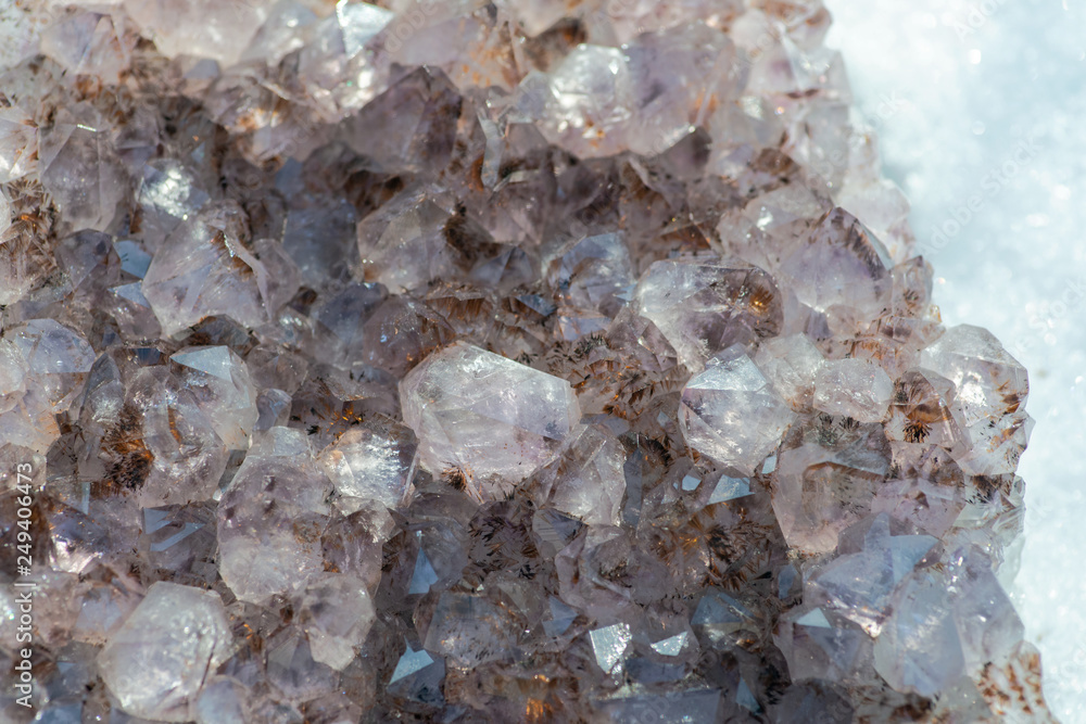 Amethyst natural crystal cluster with Goethite inclusions from Brazil on white snow at a sunny winter day. Amethyst natural crystal cluster with Goethite inclusions from Brazil on white snow at a sunny winter day.