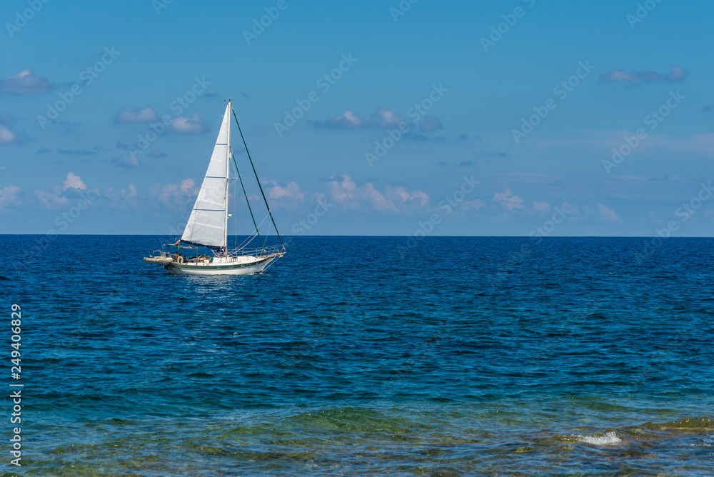 Close-up of a sailboat sailing at sea with a background of a blue sky.