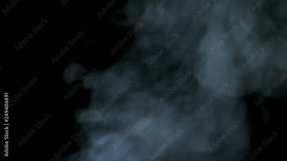 White steam rises diagonally blowing from bottom to top on black background. White steam rises diagonally blowing from bottom to top on black background.