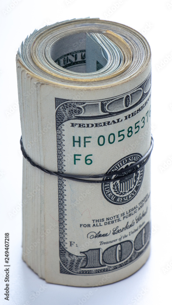 100 dollar bills twisted into tube and tied with an elastic band. white background. 100 dollar bills twisted into tube and tied with an elastic band. white background.