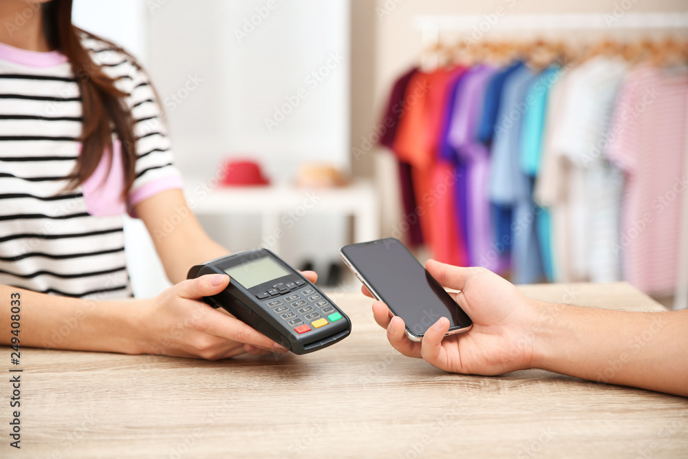 Man using payment terminal with smartphone in shop, closeup. Space for text Man using payment terminal with smartphone in shop, closeup. Space for text
