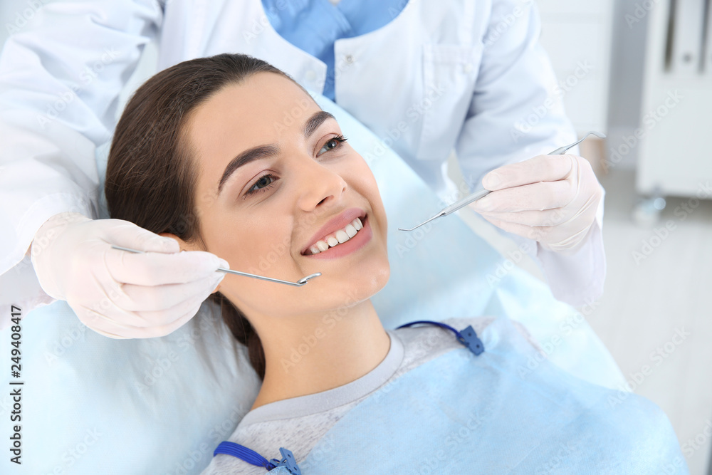 Dentist examining patient's teeth in modern clinic Dentist examining patient's teeth in modern clinic