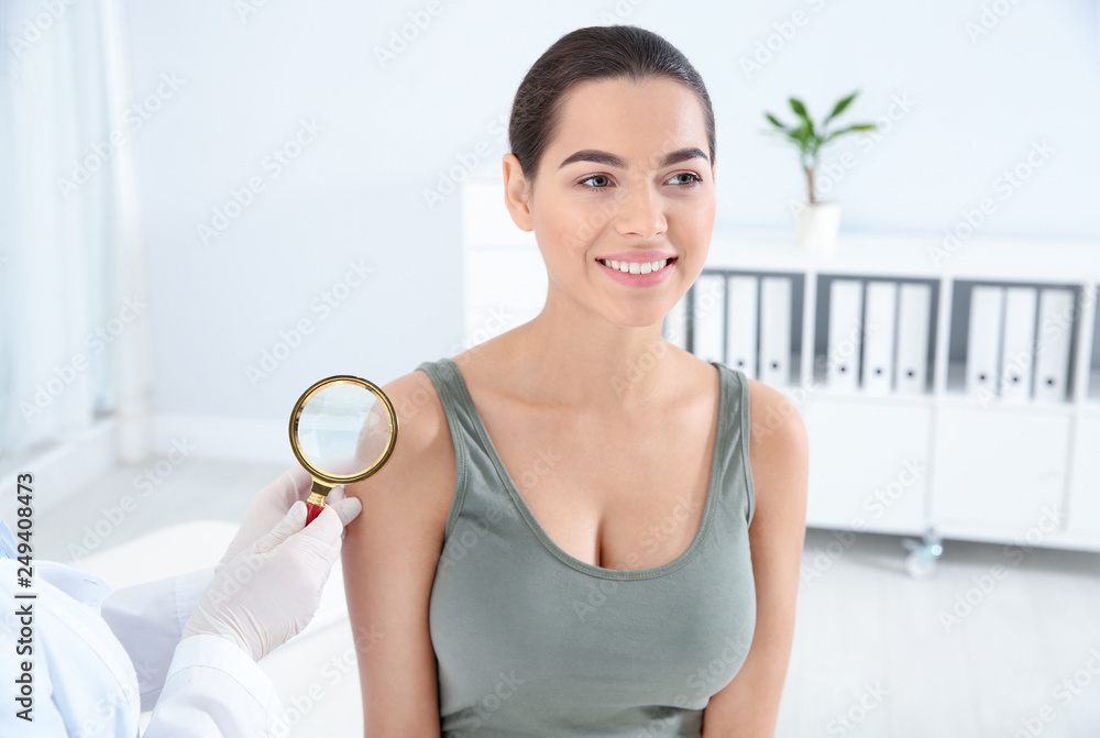 Dermatologist examining patient's birthmark with magnifying glass in clinic Dermatologist examining patient's birthmark with magnifying glass in clinic
