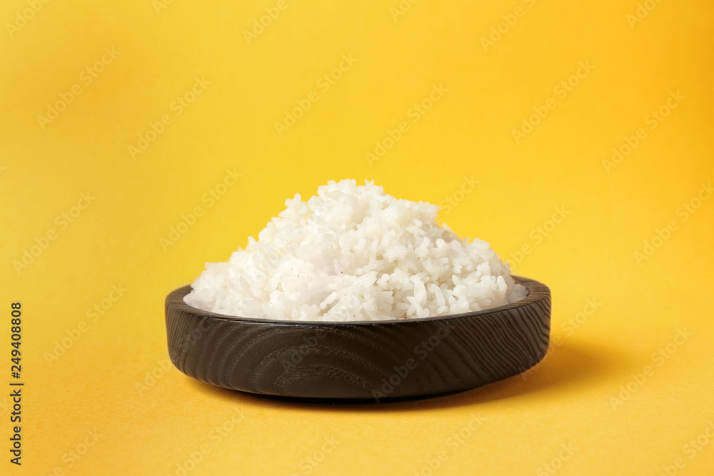 Bowl of boiled rice on color background