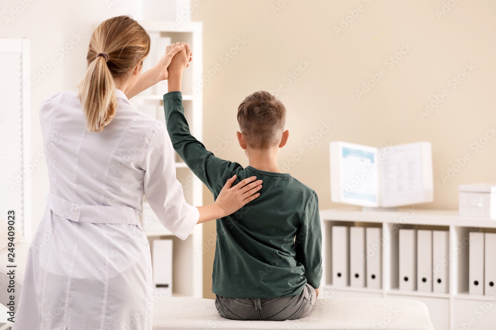 Fototapeta premium Chiropractor examining child with back pain in clinic