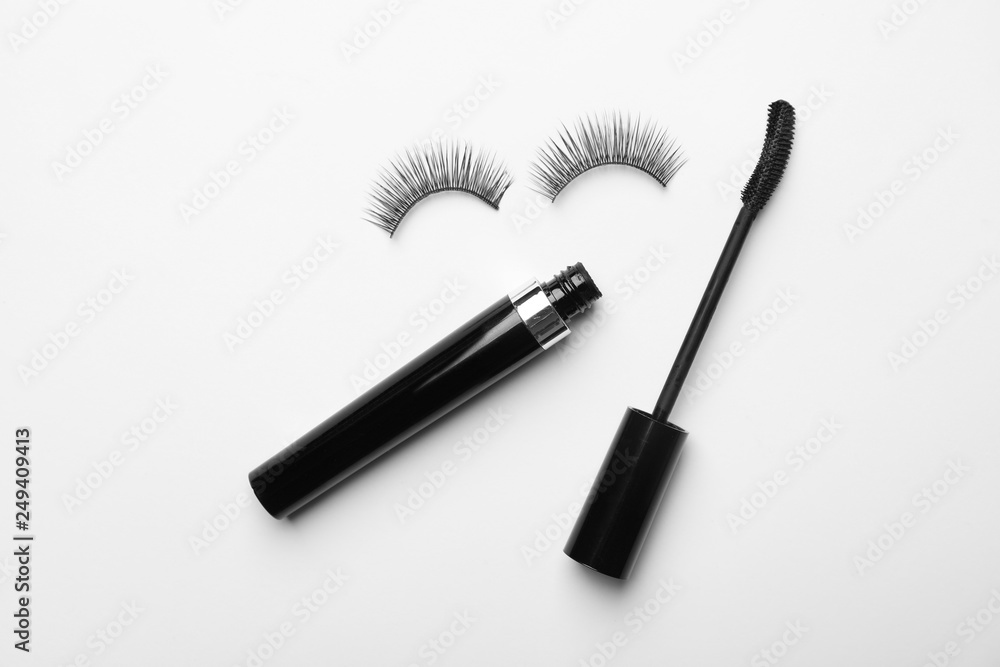 Flat lay composition of black mascara and false eyelashes on white background Flat lay composition of black mascara and false eyelashes on white background