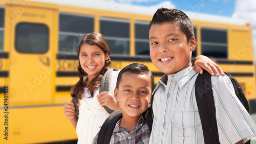 Young Hispanic Boys and Girl Walking Near School Bus photo