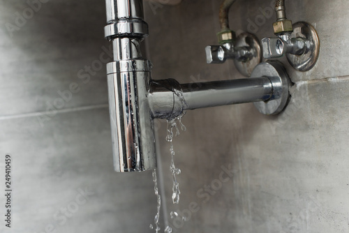 Fotografie Damaged pipe with leaking water on grey background