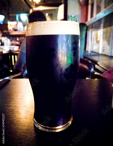 Dark stout beer on a pub background with colored lights from the environment