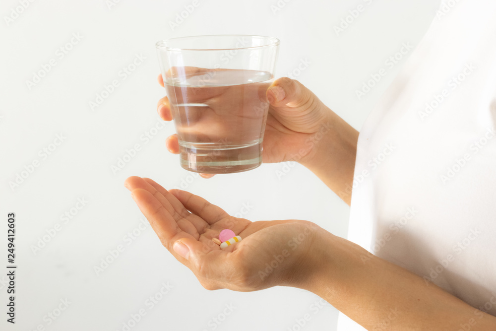 Closeup woman hand with pills medicine tablets and glass of water for headache treatment. Healthcare, medical supplements concept. Closeup woman hand with pills medicine tablets and glass of water for headache treatment. Healthcare, medical supplements concept.