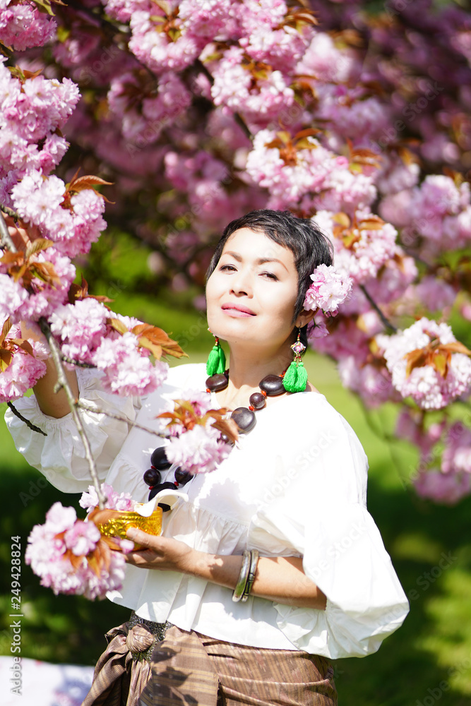 Femme en habit Thaïlandais cueillant des fleurs de Sakura au printemps