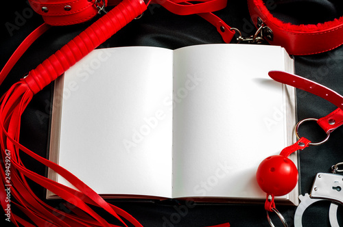 Obraz na płótnie Sexual kink and BDSM concept theme with an open book or notebook with blank white pages sounded by handcuff, whip, flogger, collar and leash, ball gag and other bondage devices with copy space w salonie
