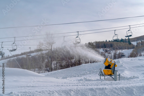 Snow canon and chair lifts on snowy mountain