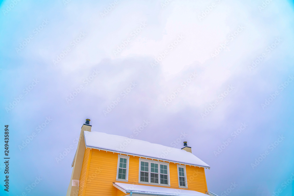 Yellow house with snow covered roof against sky Yellow house with snow covered roof against sky