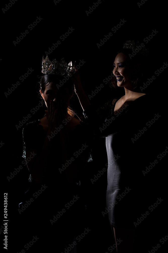 Two Silhouette Shadow Back Rim Light of Miss Pageant Beauty Queen Contest put Silver Diamond Crown on Winner final moment most beautiful woman in world universe, studio lighting dark black background