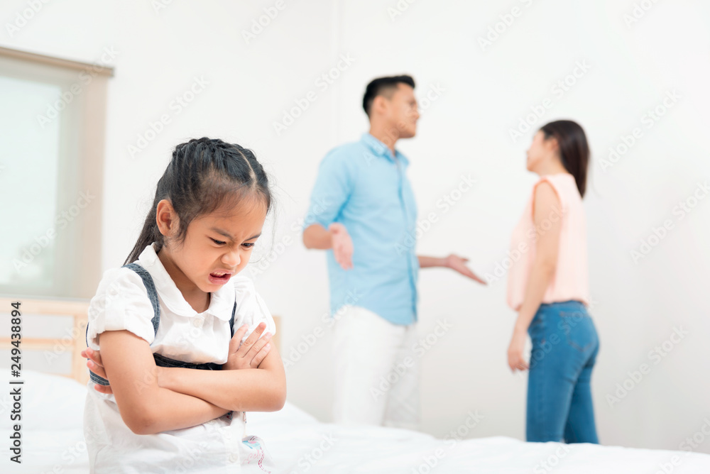 Family problem and child with background at quarrel of parents. Sad little girl is unhappy while in the bed room and cry against arguing parents at home or Conflict happened in the family