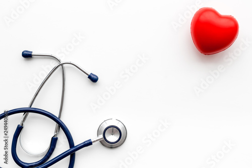 Heart health, health care concept. Stethoscope near rubber heart on white background top view copy space