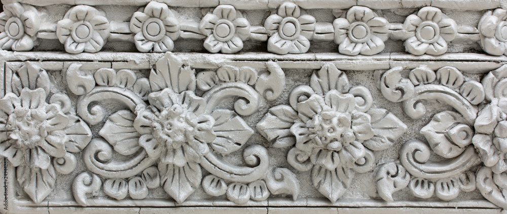 Pattern of gray flower carved on stucco design of native wall, Thai style in temple